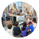 Group of children watching a man turn wood on a lathe
